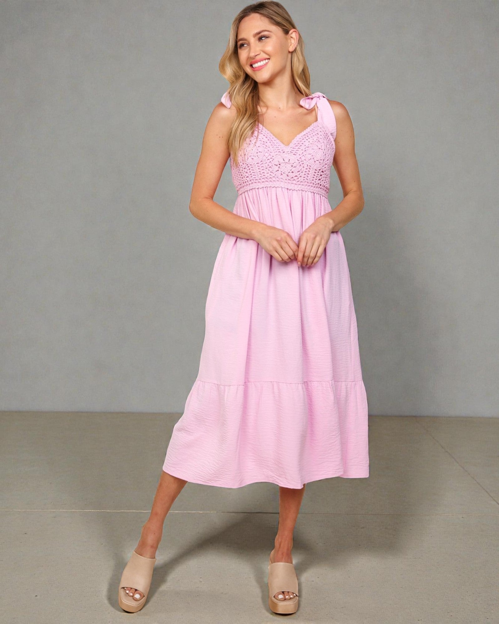 Woman wearing a pink dress against a gray background