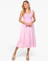 A woman modeling a light pink sleeveless midi dress with a lace-trimmed V-neck bodice and tiered skirt, paired with beige platform sandals, against a plain white studio background.