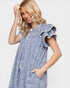 Woman wearing a blue checkered dress with ruffled sleeves on a light gray background