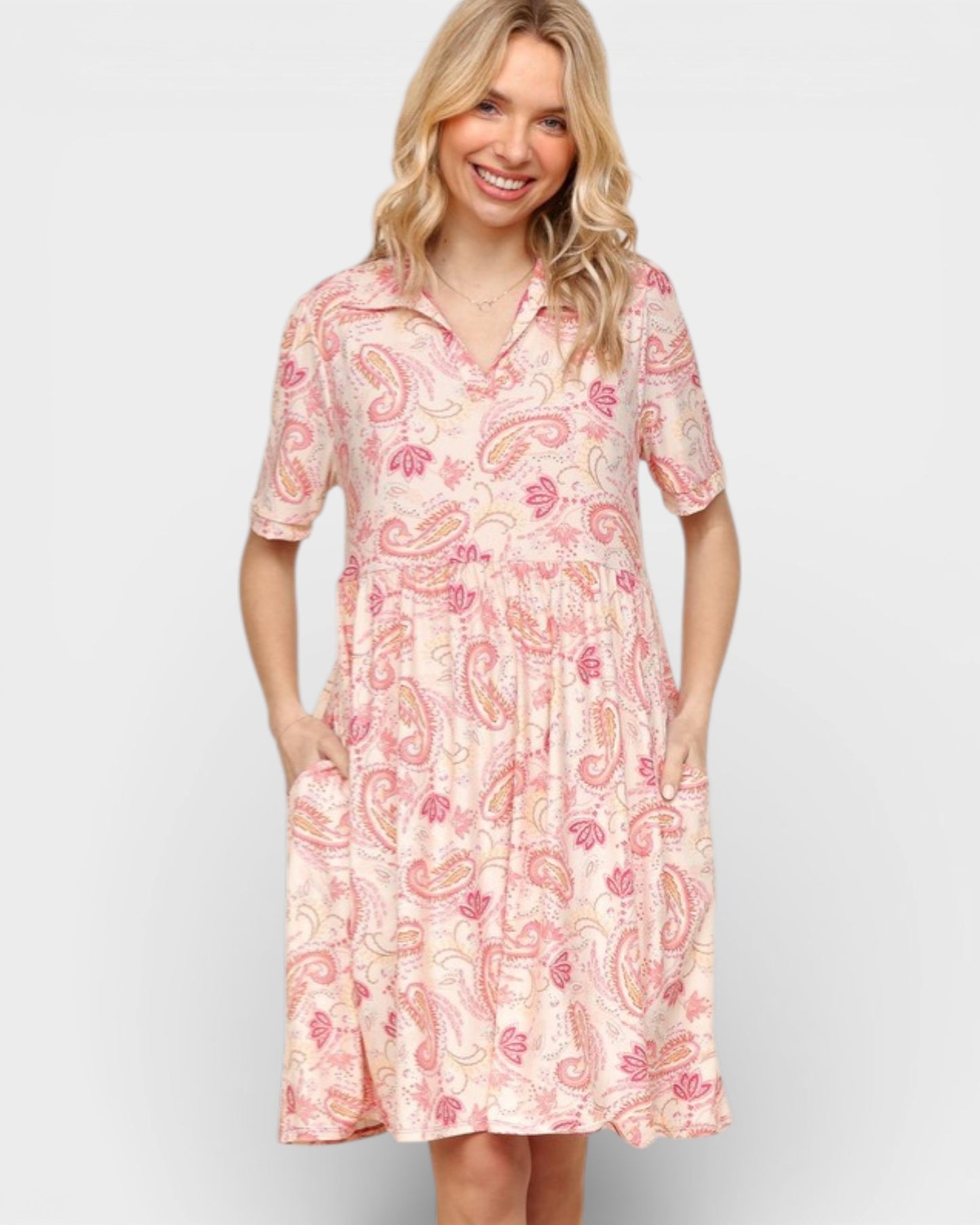 Woman wearing a pink paisley dress against a plain background