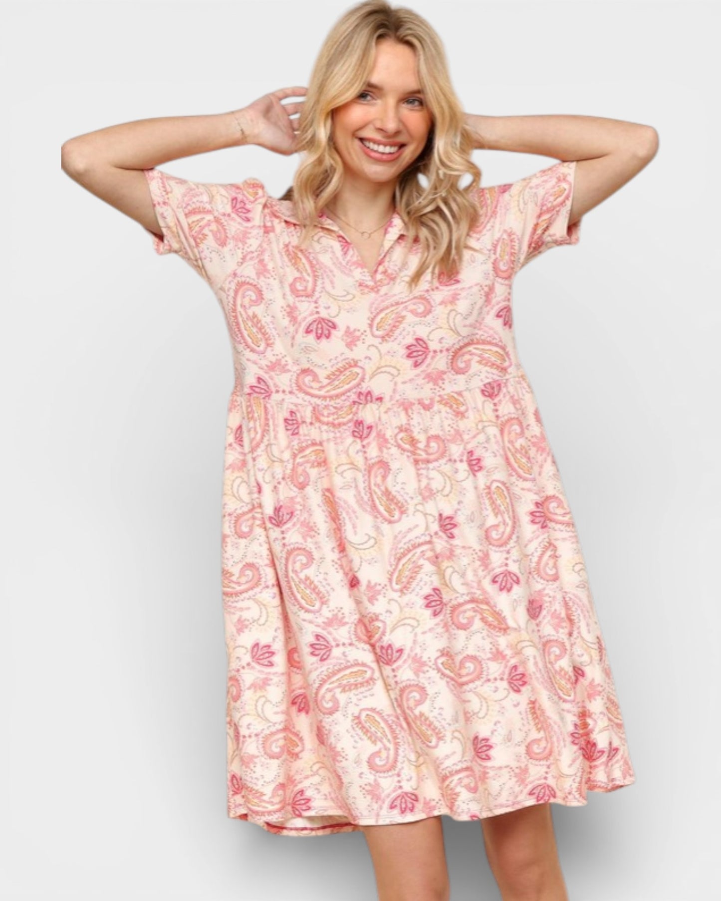 Woman wearing a pink paisley patterned dress on a light gray background