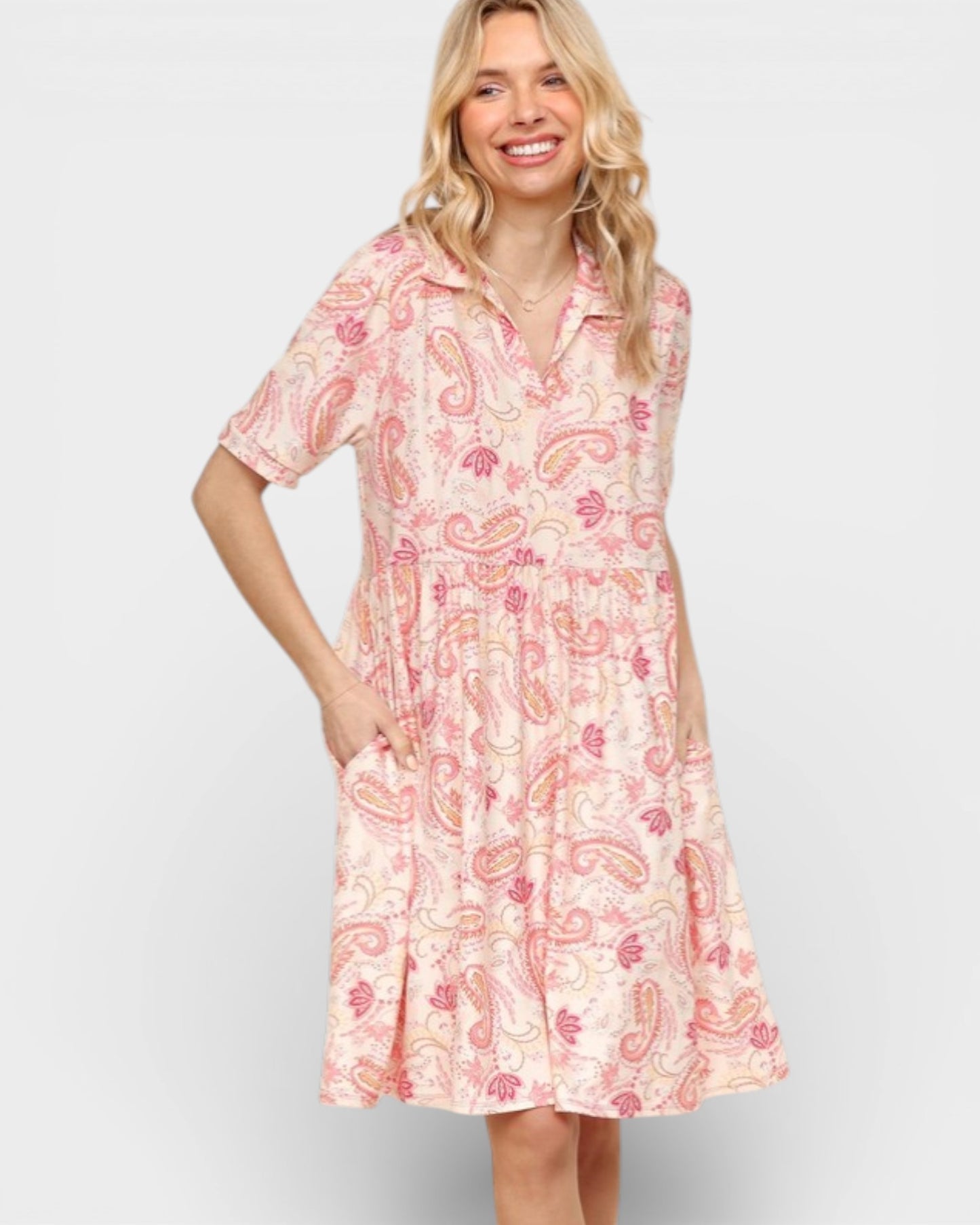 Woman wearing a pink paisley dress on a white background