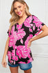 Woman wearing a black and pink floral top with denim shorts on a white background