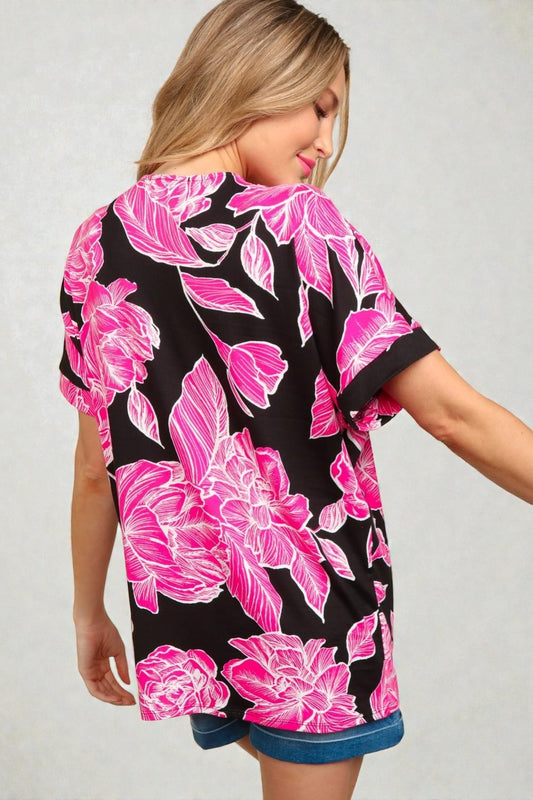 Woman wearing a black and pink floral dress against a plain background