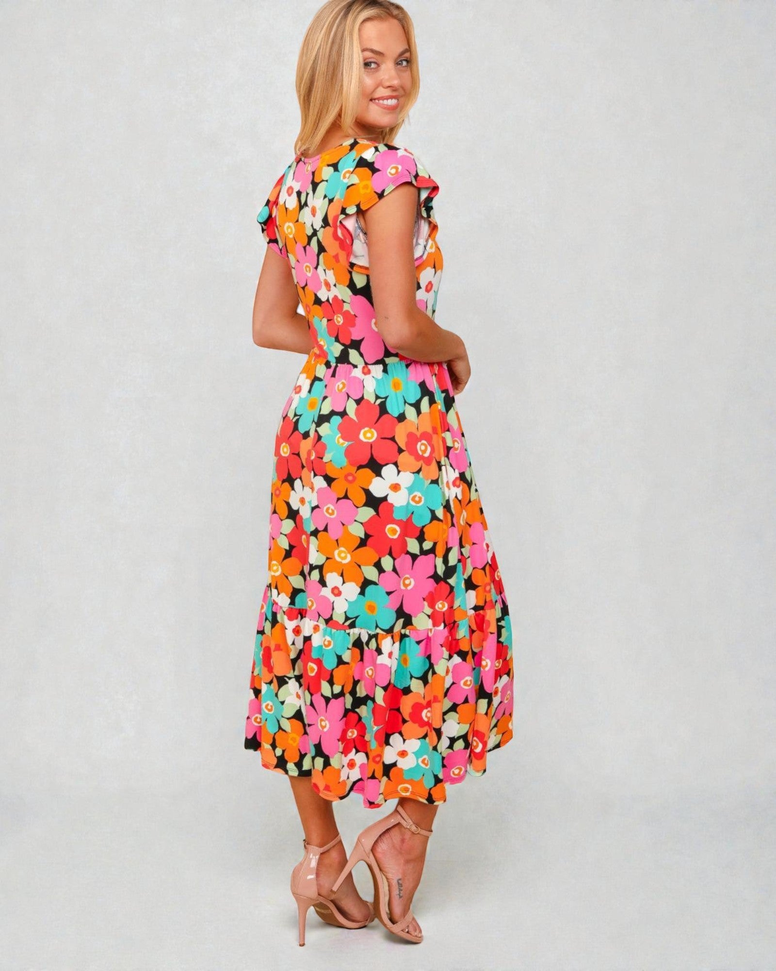 Woman wearing a colorful floral dress on a plain background