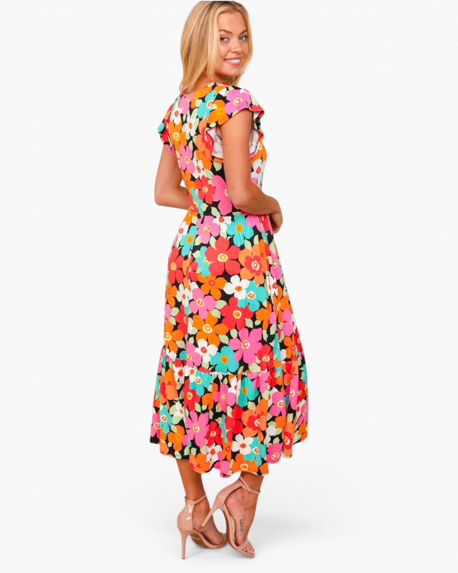 A woman modeling a colorful floral midi dress with ruffled cap sleeves, shown from a three-quarter back angle against a plain white studio background.