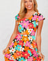 Woman wearing a colorful floral dress on a plain background