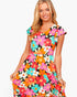 A woman modeling a short-sleeve V-neck dress with a colorful, dense retro floral pattern on a black background, set against a plain white studio backdrop.