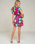 Woman wearing a colorful floral dress on a light gray background