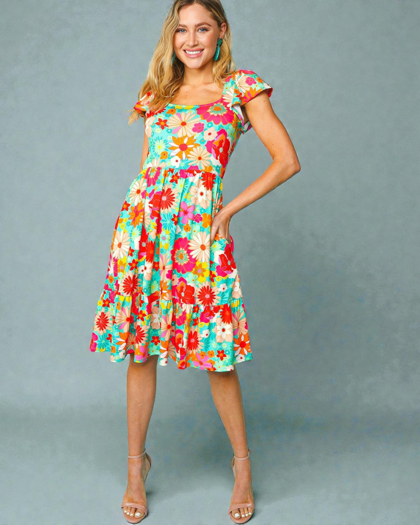 Woman wearing a colorful floral dress against a gray background