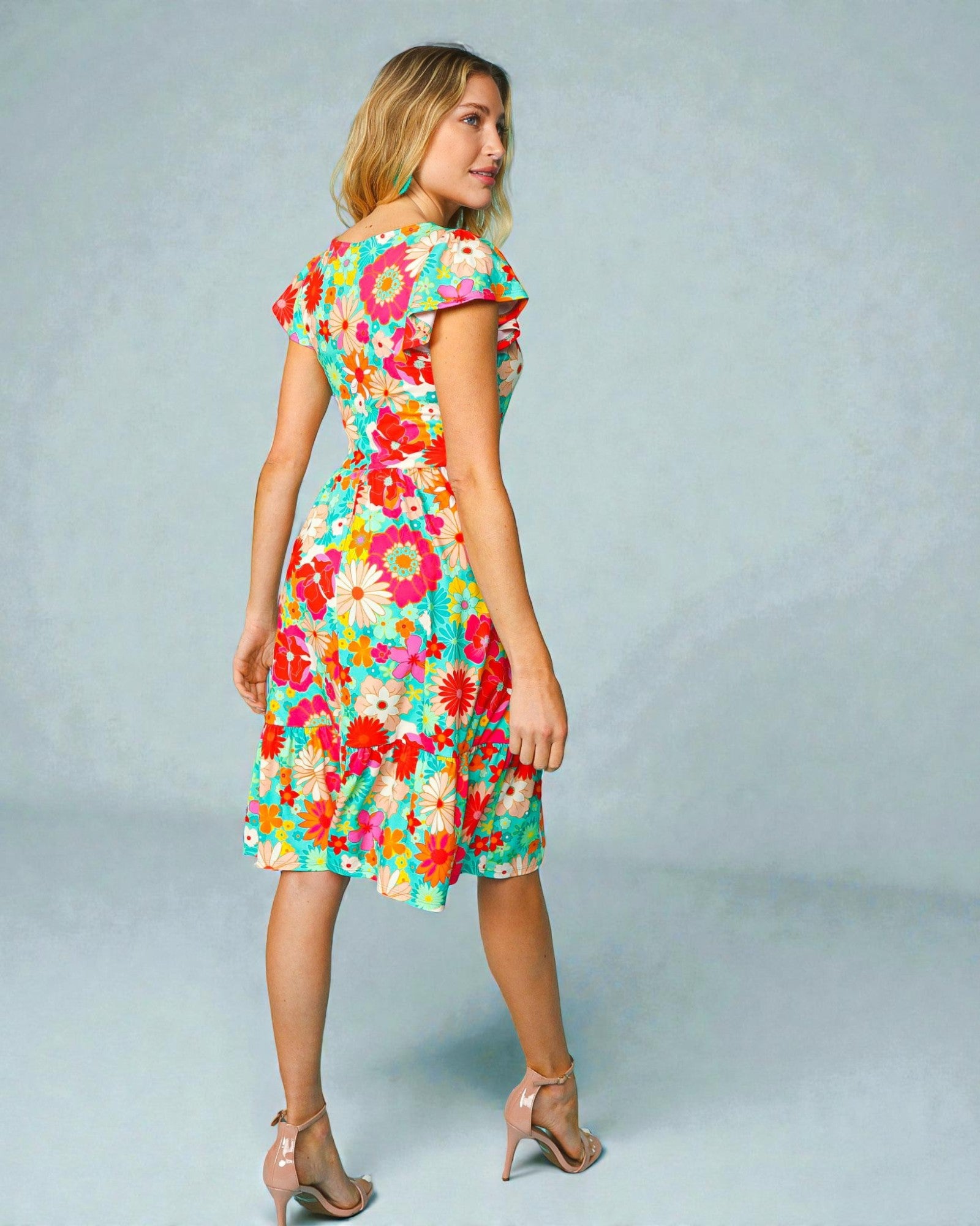 Woman wearing a colorful floral dress on a light gray background