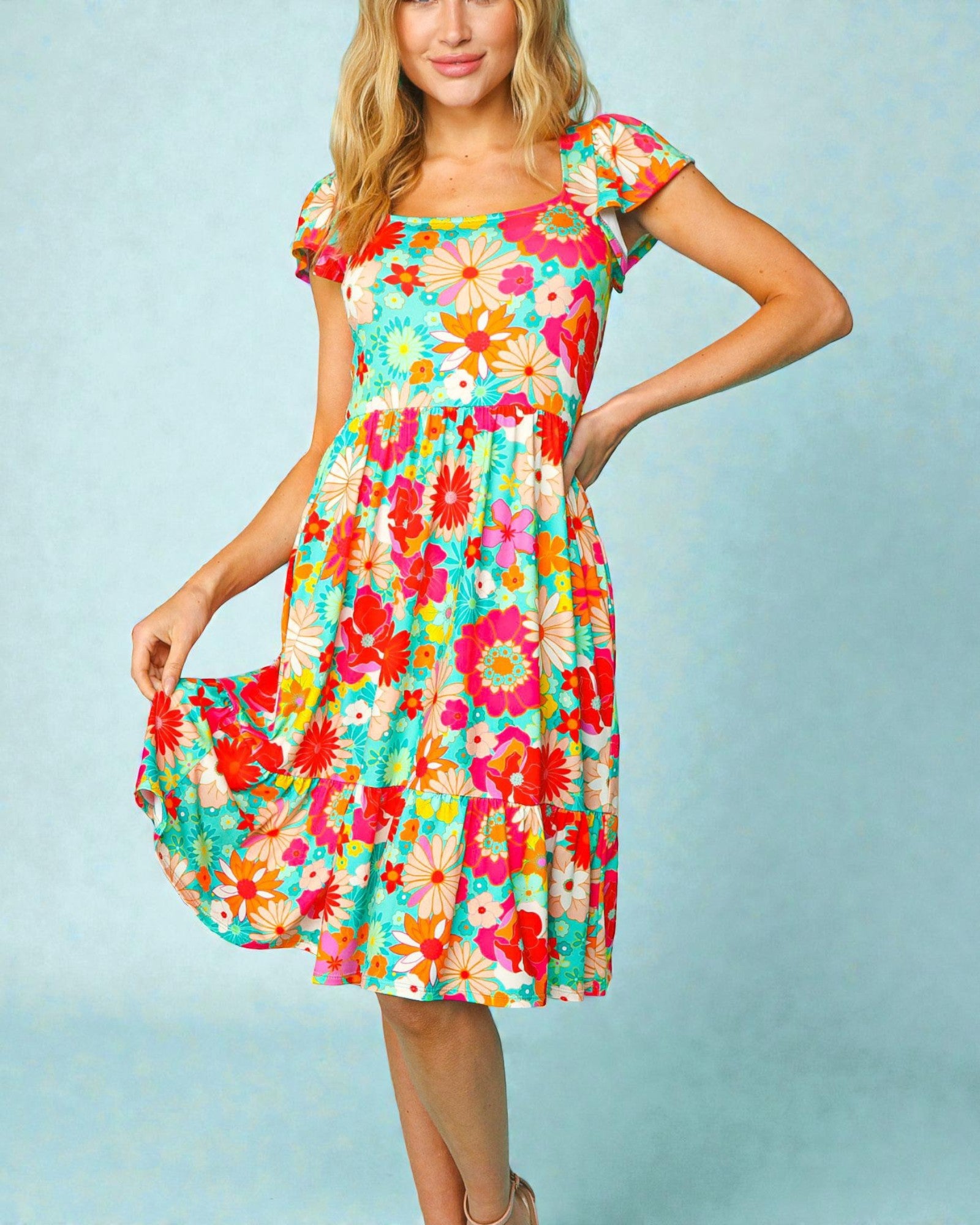 Woman wearing a colorful floral dress against a light blue background
