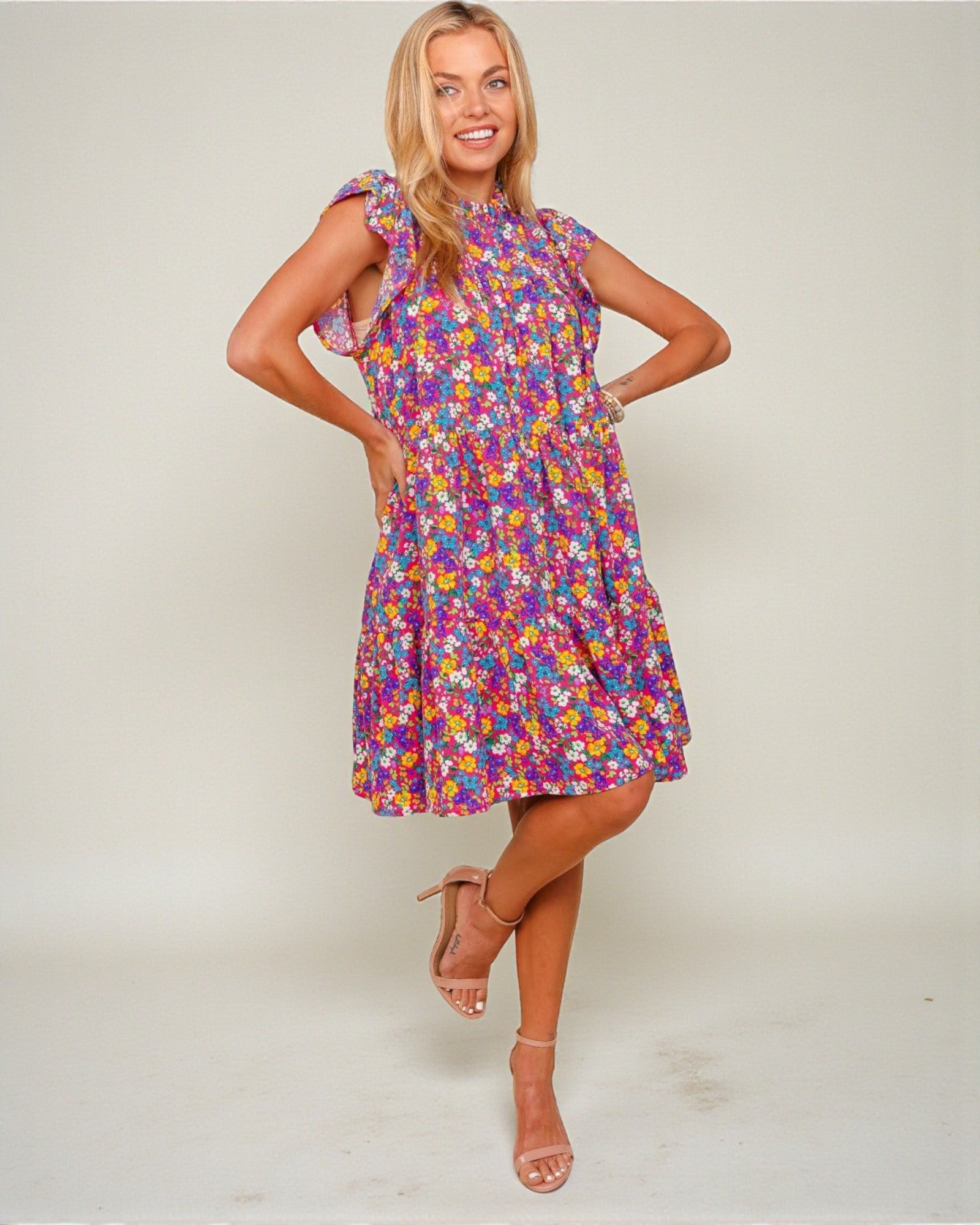 Woman wearing a colorful floral dress against a plain background