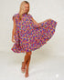 Woman wearing a colorful floral dress against a white background