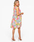 A woman modeling a sleeveless knee-length dress with a colorful geometric patchwork print, shown from a three-quarters back angle against a plain white studio background.