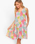 A woman modeling a sleeveless V-neck A-line dress with a colorful patchwork floral print in pink, teal, green, and cream on a light gray background.