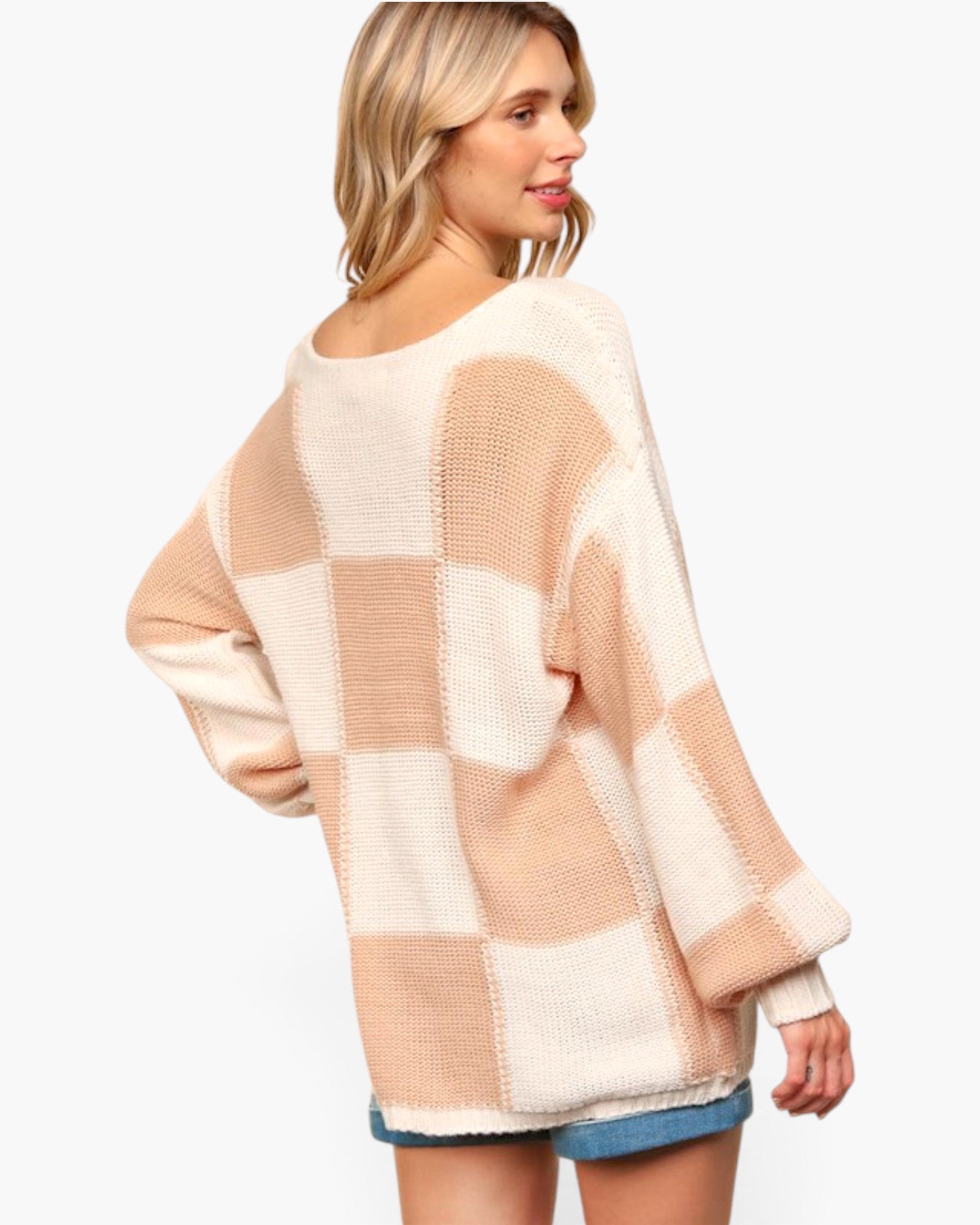 A woman wearing an oversized knit sweater with a beige and cream checkered pattern, shown from a three-quarters back view against a plain white background.