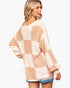 A woman wearing an oversized knit sweater with a beige and cream checkered pattern, shown from a three-quarters back view against a plain white background.