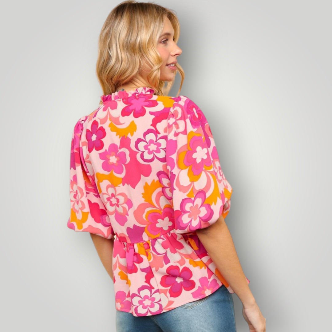 Woman wearing a pink floral blouse against a gray background