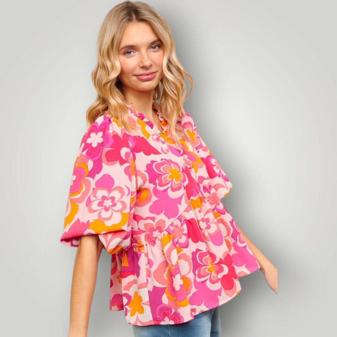 Woman wearing a colorful floral blouse against a gray background