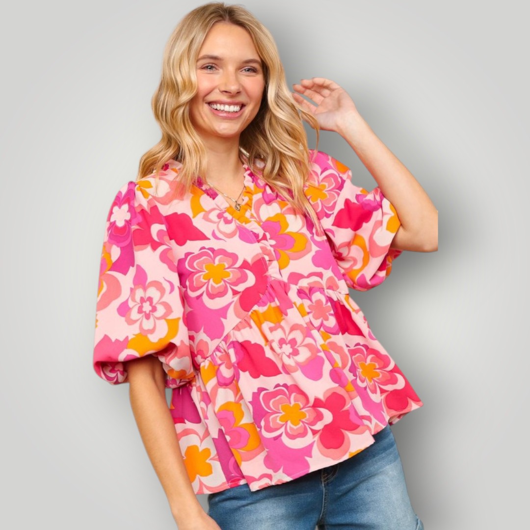 Woman wearing a colorful floral blouse against a gray background