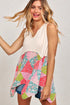 Woman wearing a sleeveless top with a colorful pattern over a plain top.