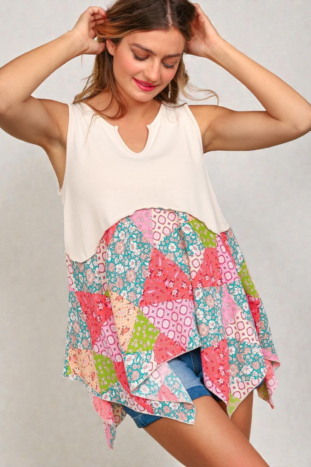 Woman wearing a white sleeveless top with a colorful patchwork skirt on a plain background