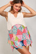 Woman wearing a white sleeveless top with a colorful patchwork skirt on a plain background