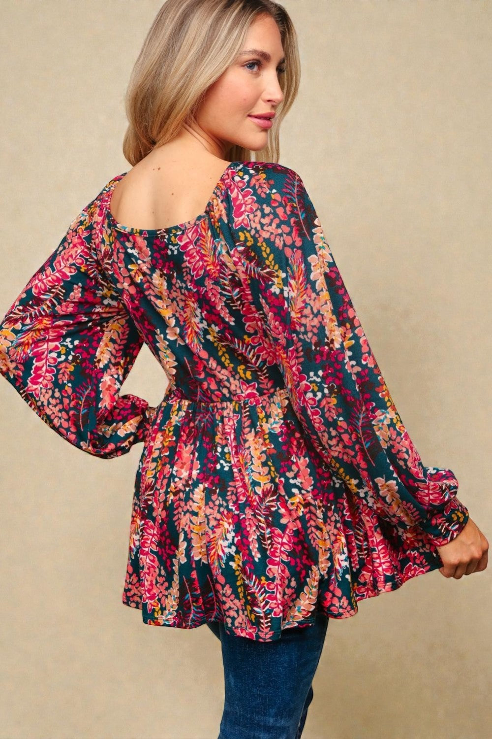 Woman wearing a colorful floral dress with long sleeves on a beige background