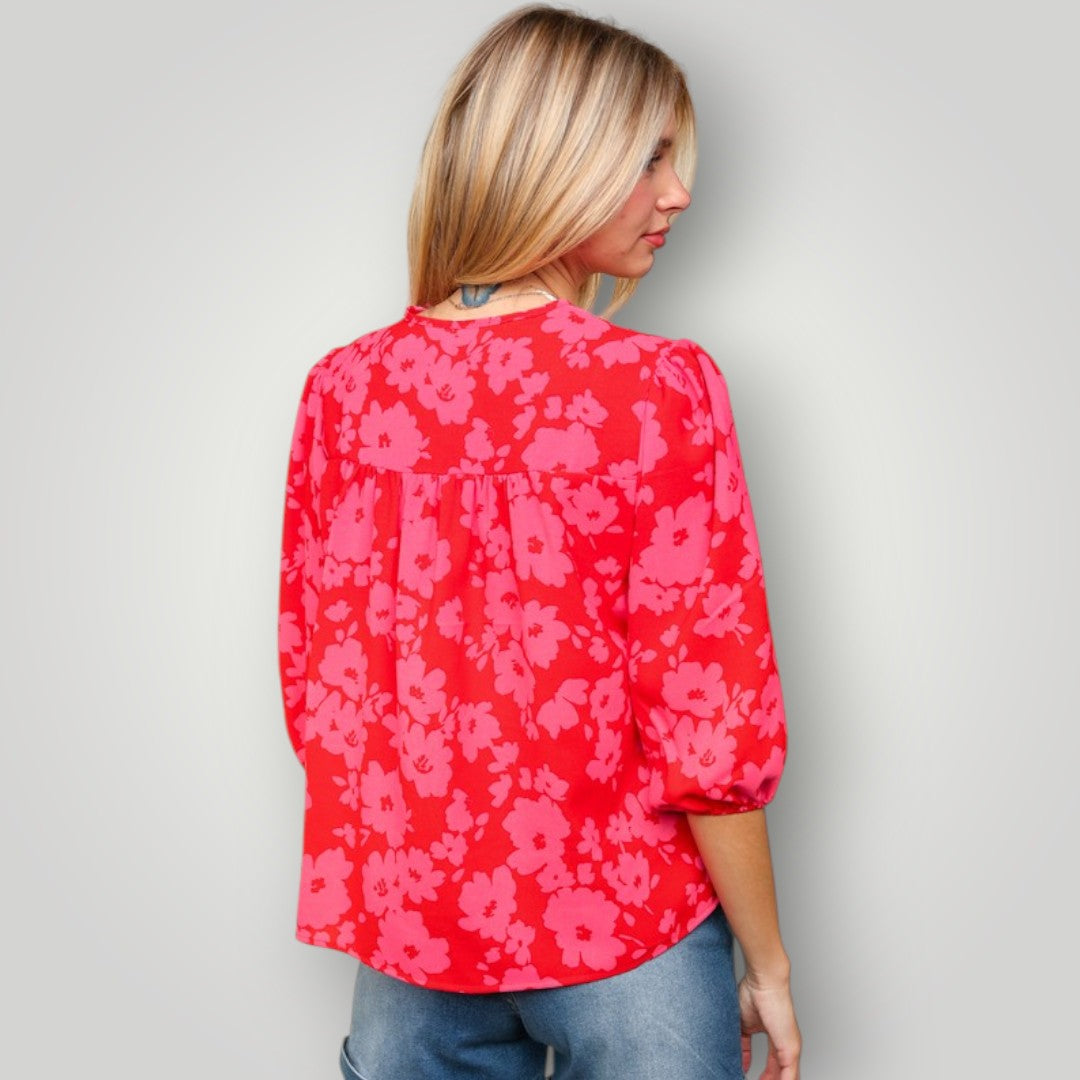 Woman wearing a red floral blouse against a plain background