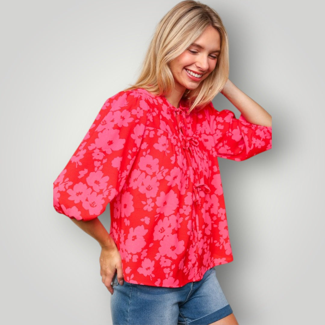 Woman wearing a red floral blouse against a gray background
