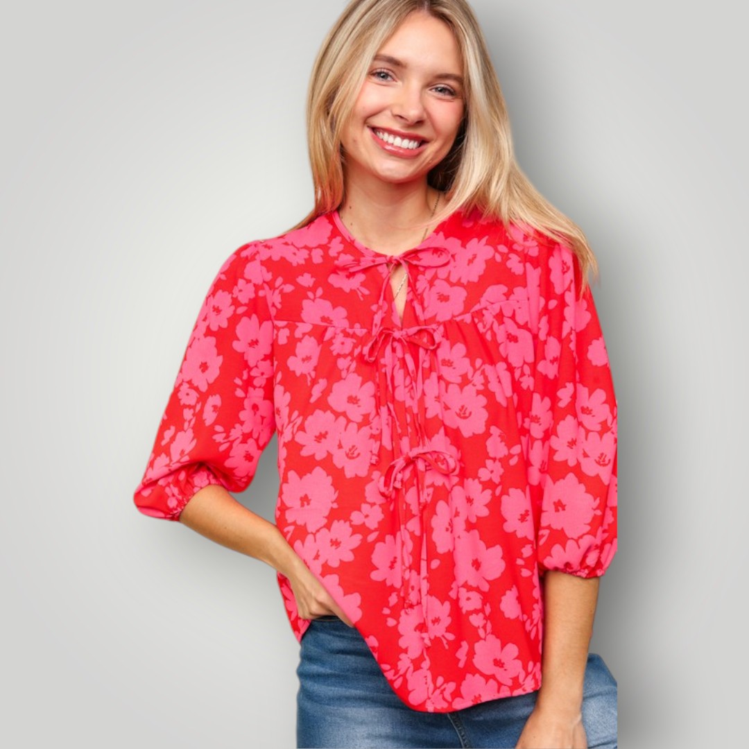 Woman wearing a red floral blouse against a gray background
