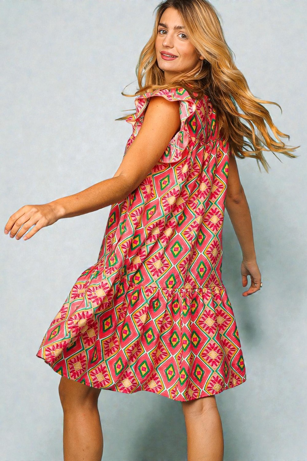 Woman wearing a pink patterned dress against a light gray background