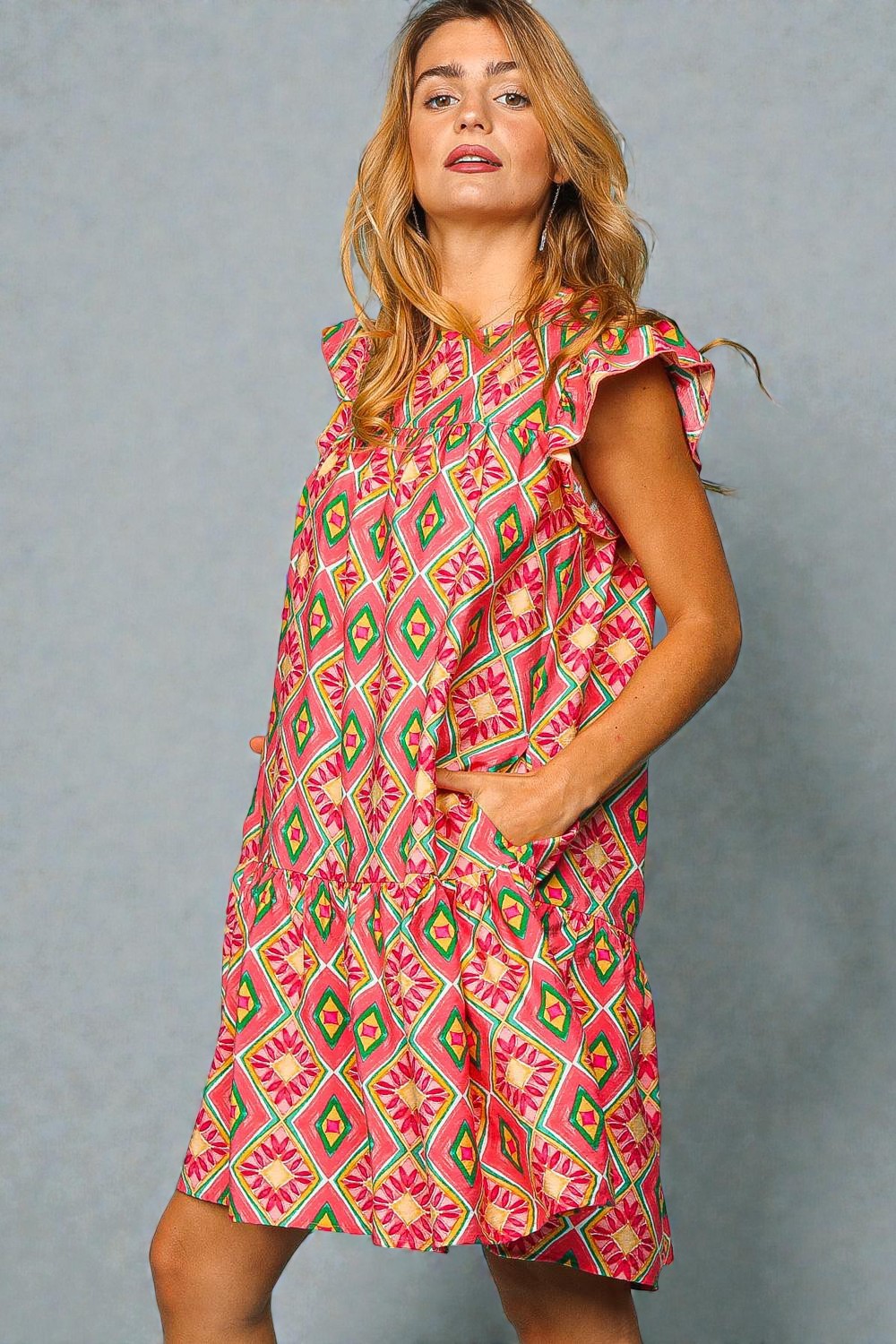 Woman wearing a colorful patterned dress against a gray background