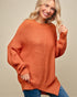 Woman wearing a rust-colored sweater against a beige background