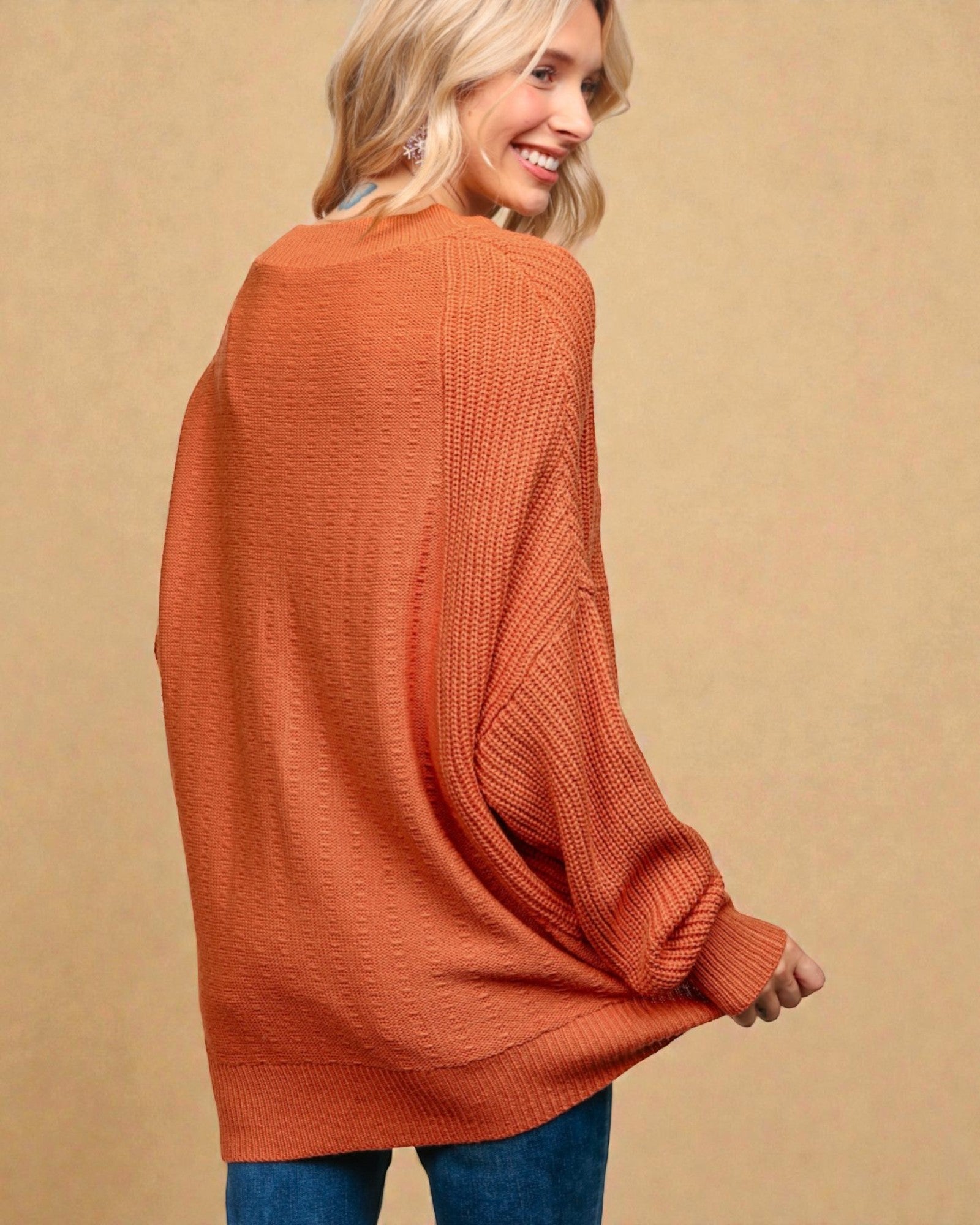 Woman wearing a rust-colored sweater against a beige background