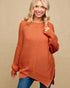 Woman wearing a rust-colored sweater against a beige background