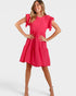 A woman modeling a bright pink tiered shift dress with ruffled short sleeves, standing against a light gray studio background.