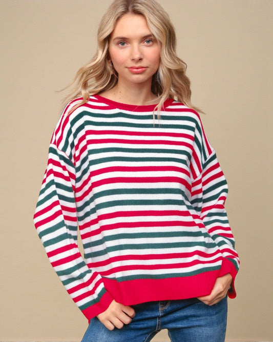 Woman wearing a red, green, and white striped sweater against a beige background