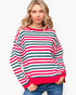 A woman wearing a long-sleeve knit sweater with horizontal red, green, and white stripes, paired with blue jeans, against a plain white background.