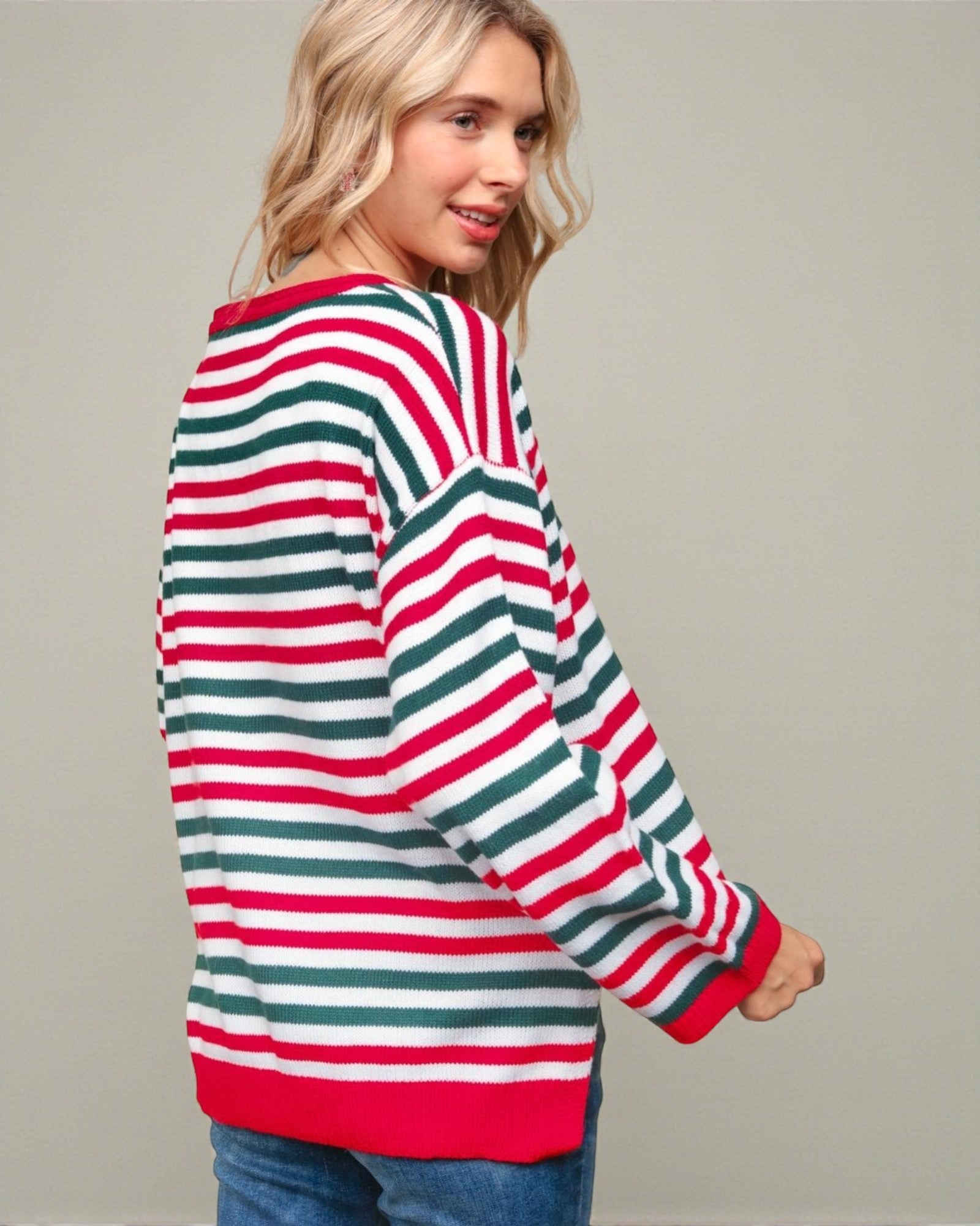 Woman wearing a red, green, and white striped sweater on a plain background
