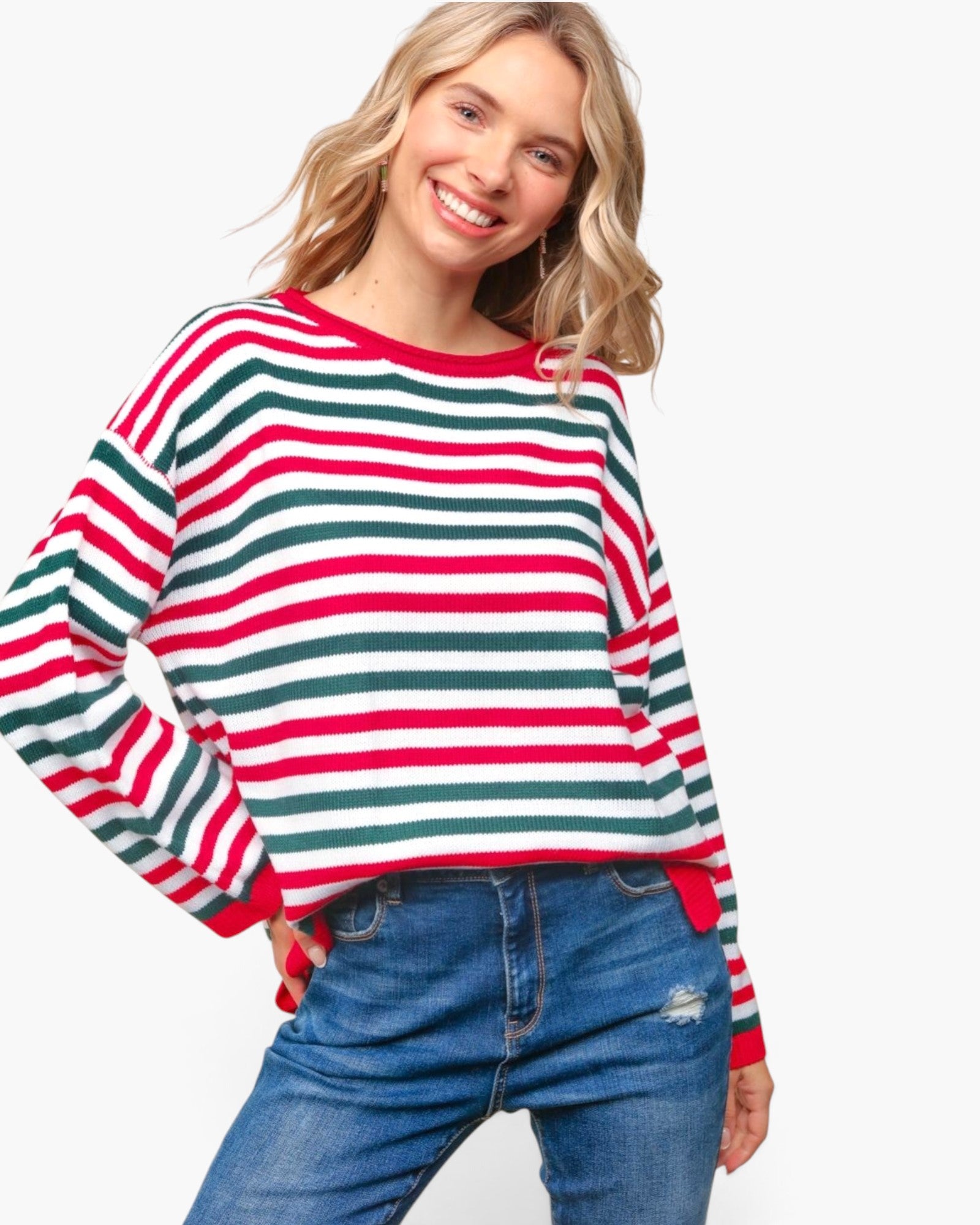 A woman wearing a long-sleeve crewneck sweater with horizontal red, green, and white stripes, paired with blue jeans, against a plain white background.