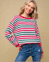 Woman wearing a red, green, and white striped sweater with blue jeans on a beige background