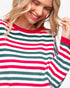 A smiling blonde woman wearing a ribbed knit long-sleeve sweater with horizontal stripes in red, green, and white, photographed against a clean white background.