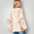 Woman wearing a colorful striped sweater against a plain background