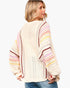 A woman wearing a cream-colored crochet knit sweater with pastel pink, yellow, and brown striped details on the sleeves, shown from a three-quarters back view against a light gray background.
