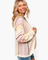 A woman wearing a cream-colored open-knit cardigan sweater with colorful striped patterns on the sleeves and body, paired with blue jeans, against a plain white background.