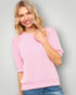 Woman wearing a pink sweater against a gray background