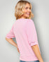 Woman wearing a pink sweater against a gray background