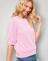 Woman wearing a pink sweater against a gray background